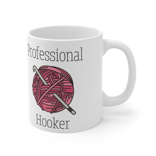 White mug with pink yarn ball and knitting needle design, text 'Professional Hooker' on a white background
